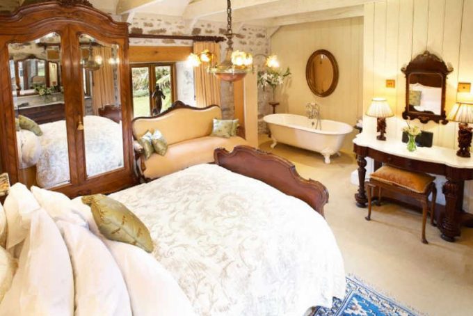 Large opulent master bedroom with roll top bath